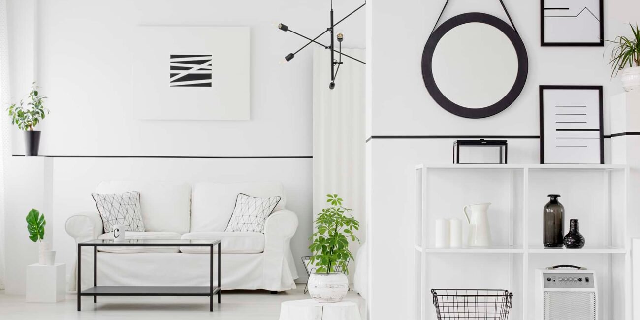 Black and white living room interior with couch, table, shelves, ornaments, posters and plants